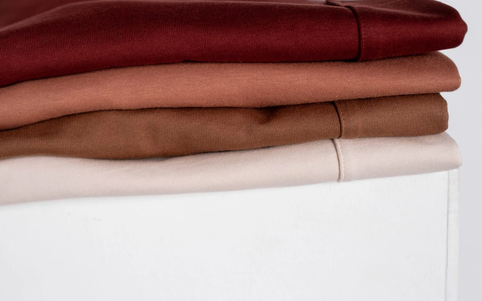 Neatly folded neutral-coloured everyday clothing showing different fabric textures