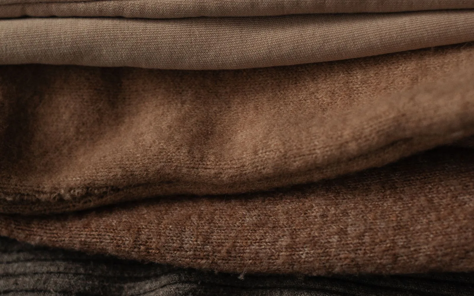 Close-up stack of folded fabrics showing different weights and textures